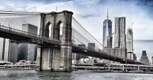 El Puente de Brooklyn, que atravesando el East River une los distritos de Manhattan y de Brooklyn, está construido con piedra caliza, granito y cemento, en un estilo arquitectónico neogótico.